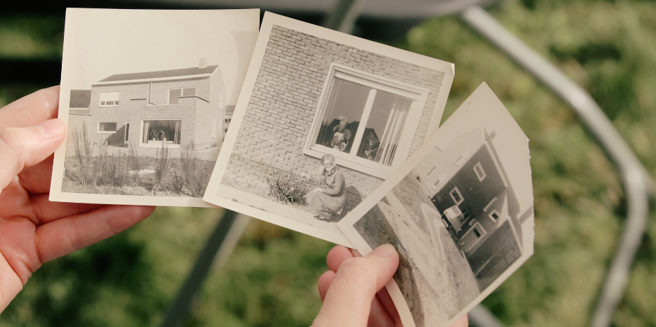 Hands holding old photographs of homes and a woman, offering inspiration for family conversation starters.